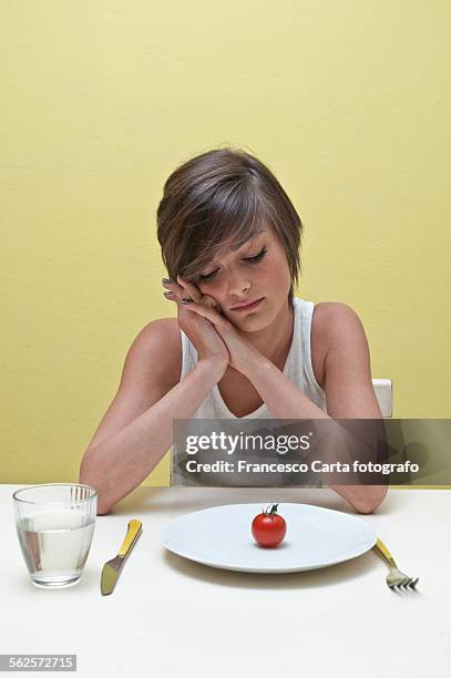 young woman looking at plate of tomato - anorexie nerveuse photos et images de collection