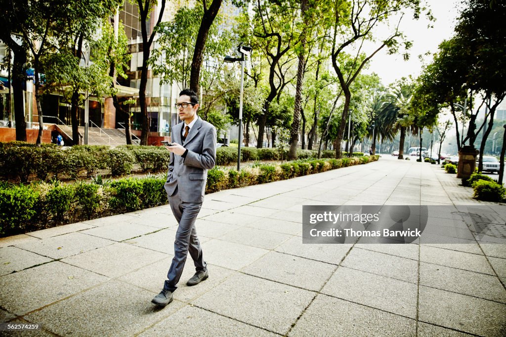 Businessman on sidewalk looking at smartphone