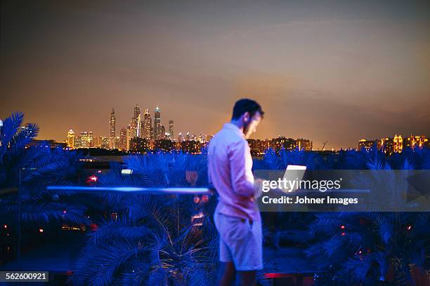 man using laptop on terrace, cityscape on background - dubai palm stock pictures, royalty-free photos & images