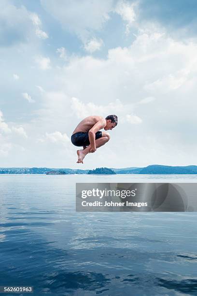 man jumping into sea - agua estancada fotografías e imágenes de stock