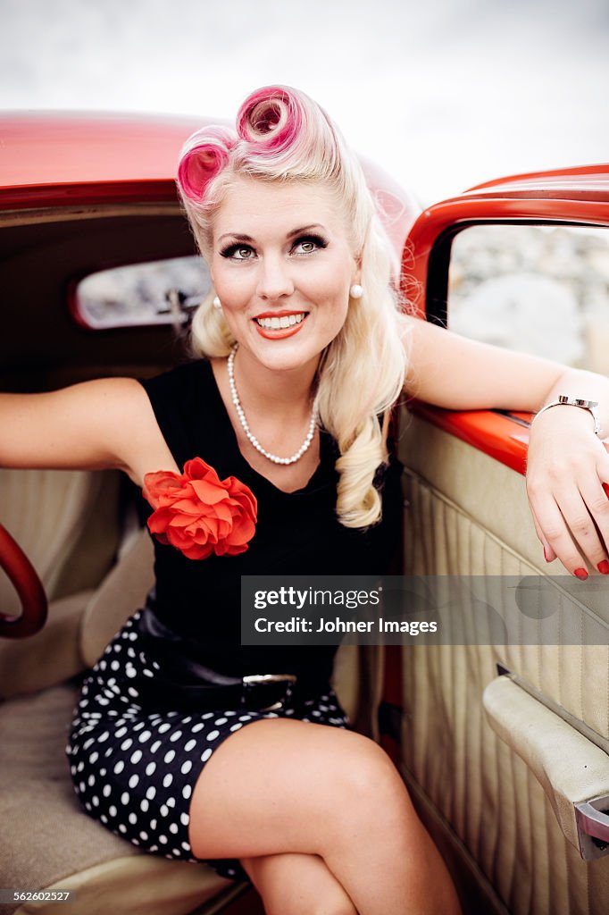 Woman wearing retro clothes sitting in vintage car