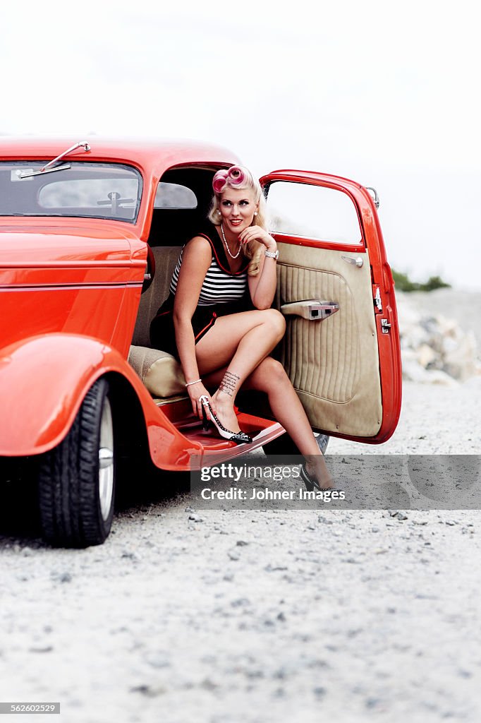 Woman wearing retro clothes sitting in vintage car