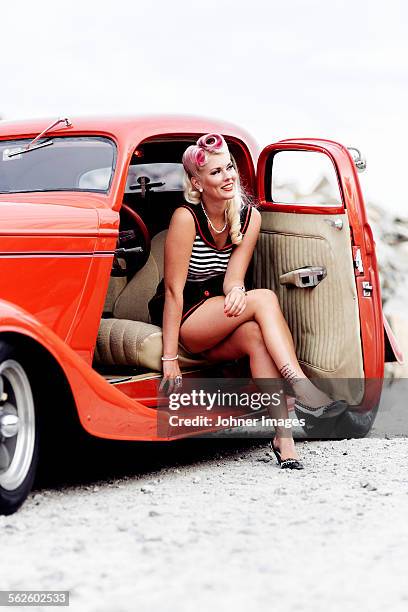 woman wearing retro clothes sitting in vintage car - rockabilly stockfoto's en -beelden