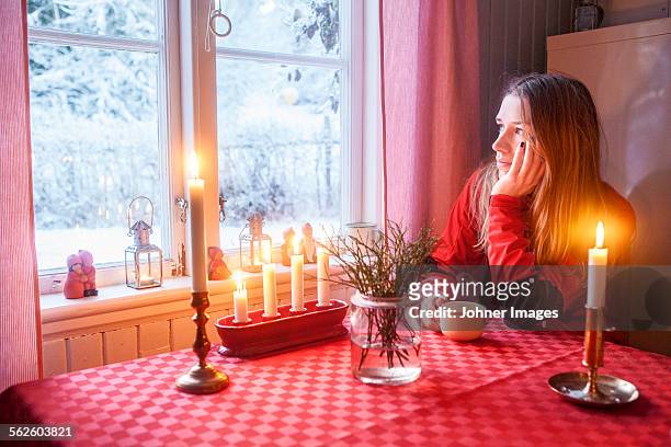 young woman looking through window - johner christmas bildbanksfoton och bilder