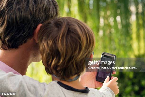 father and son posing for photograph with smartphone - famiglia multimediale foto e immagini stock
