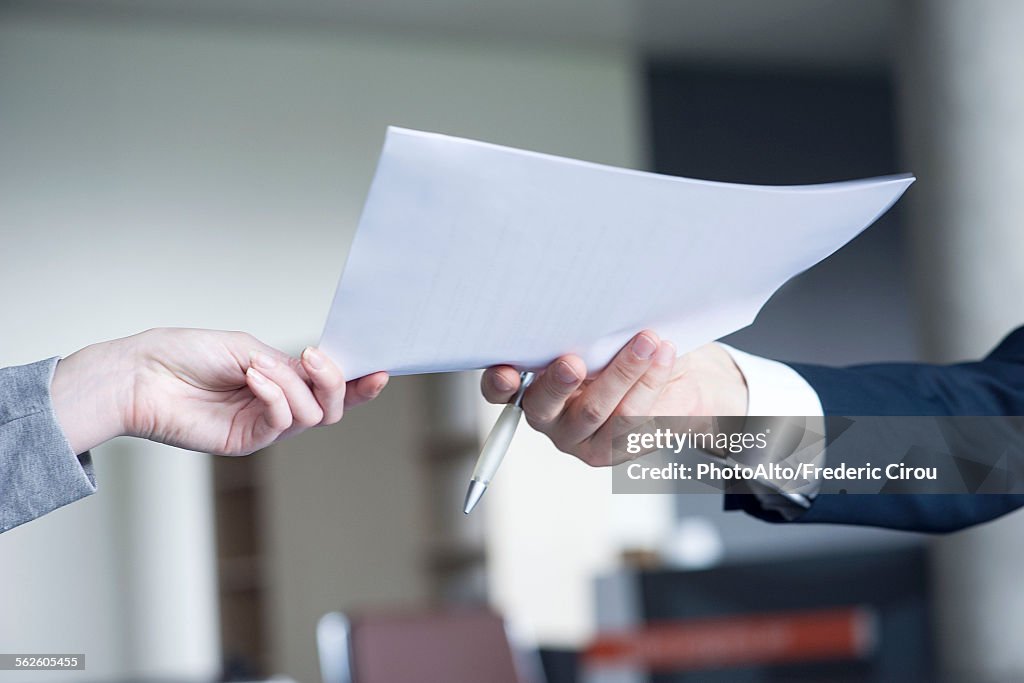 Businessman handing document to colleague, cropped