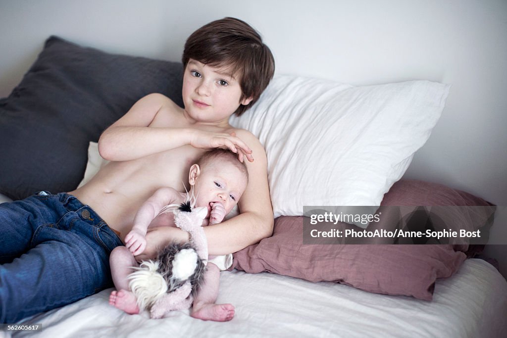 Boy resting on bed with baby brother