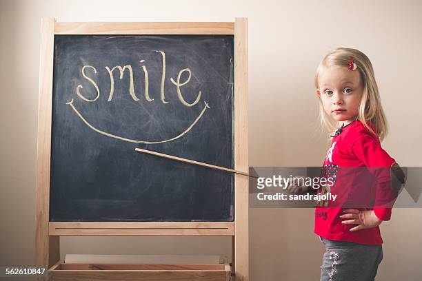 little girl pointing at the word smile on a blackboard - girl pointing bildbanksfoton och bilder