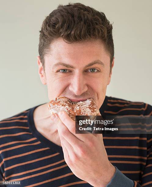 portrait of man eating donut - donut man stock pictures, royalty-free photos & images