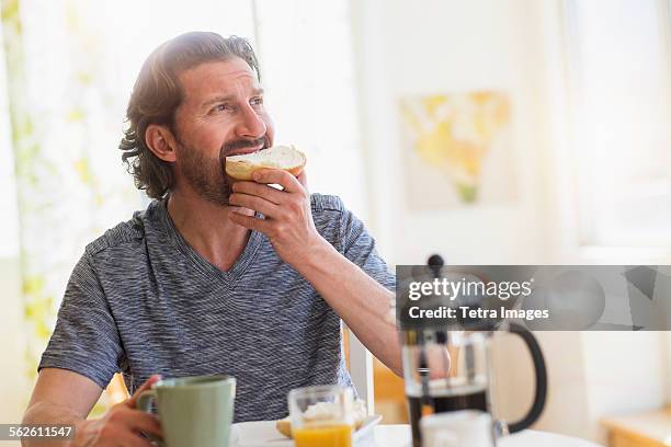 mature man eating breakfast - eating bread stockfoto's en -beelden