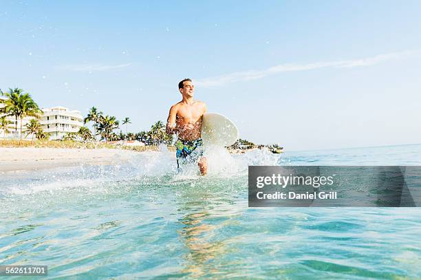 usa, florida, west palm beach, young surfer running - west palm beach ストックフォトと画像