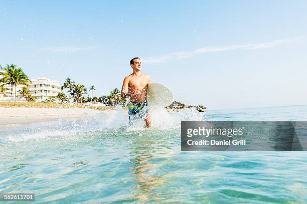 usa, florida, west palm beach, young surfer running - west palm beach stock pictures, royalty-free photos & images
