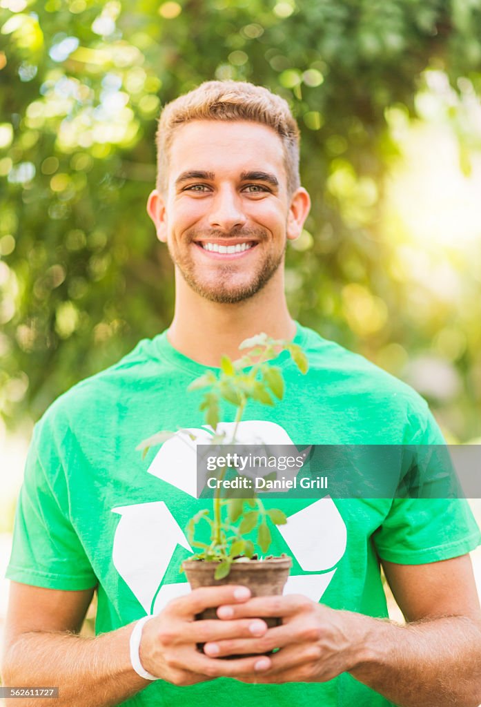 Portrait of young man holding potted plant