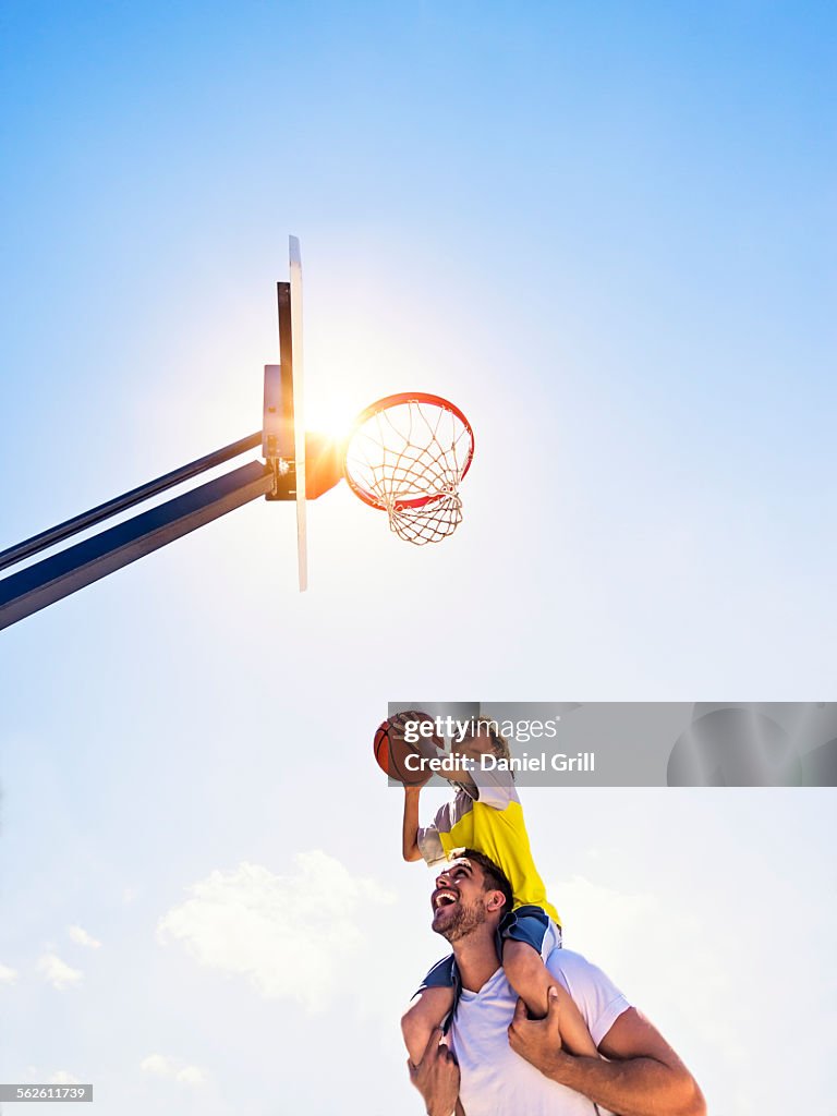 Boy (8-9) playing basketball with his brother