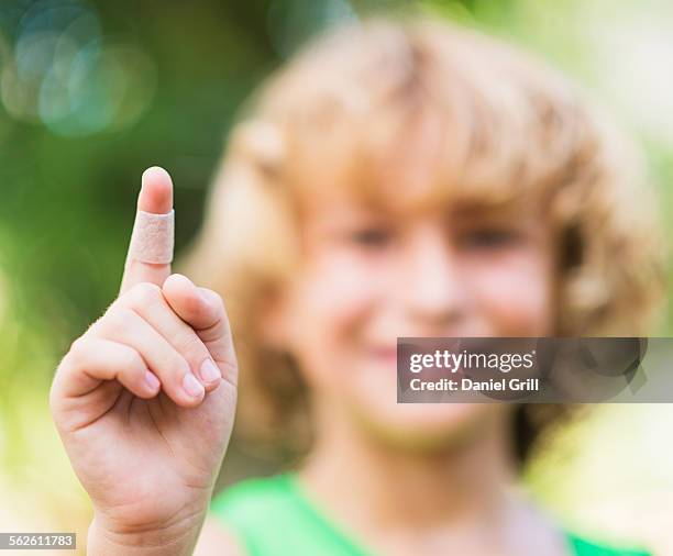 portrait of boy (8-9) with adhesive bandage on his finger - doigt levé photos et images de collection