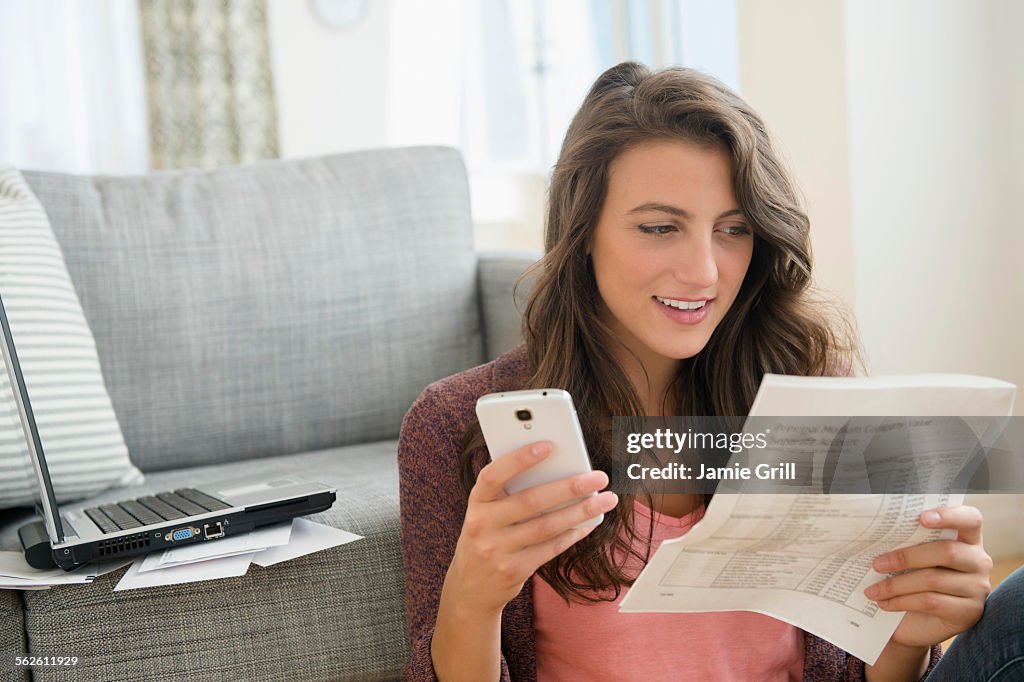 Woman in living room with papers and smartphone