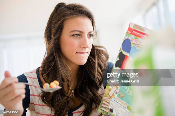 woman eating cereal reading info on box - cereal boxes stock pictures, royalty-free photos & images