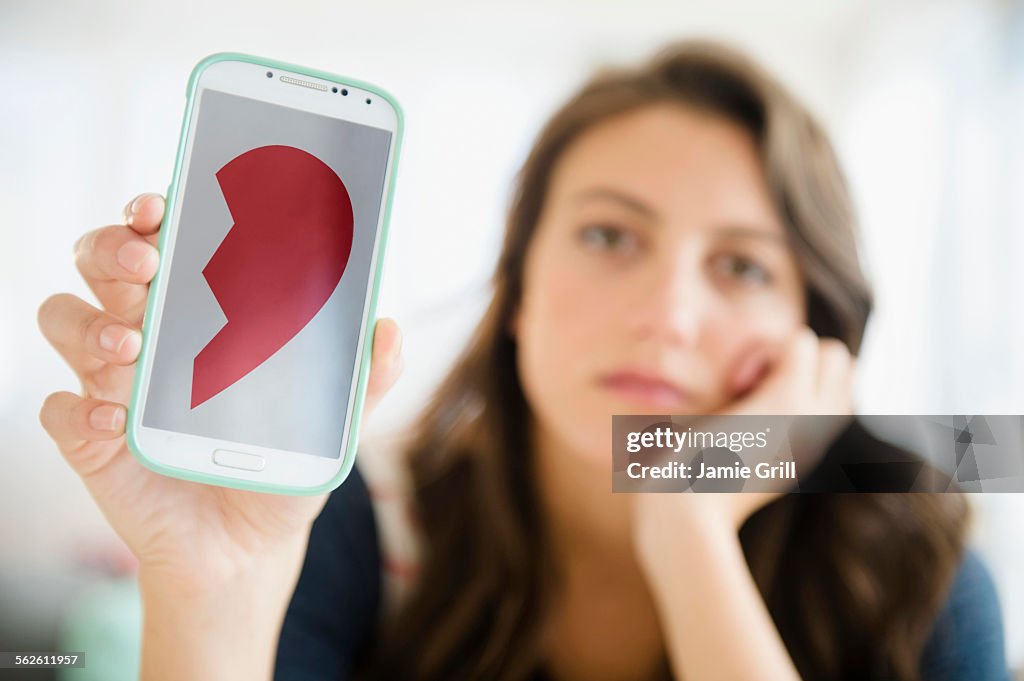 Woman showing image of broken heart on her smartphone