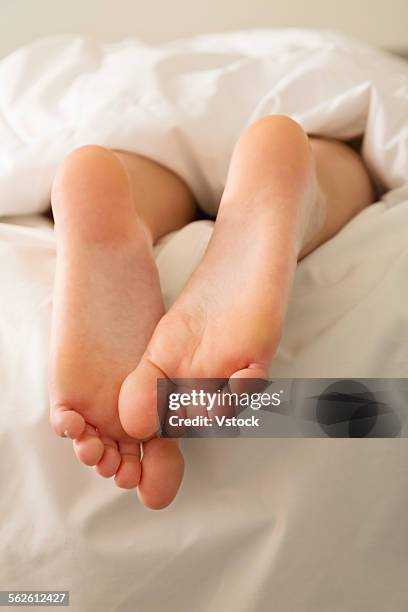 rear view of bare feet, person in white bedding - womans bare feet fotografías e imágenes de stock