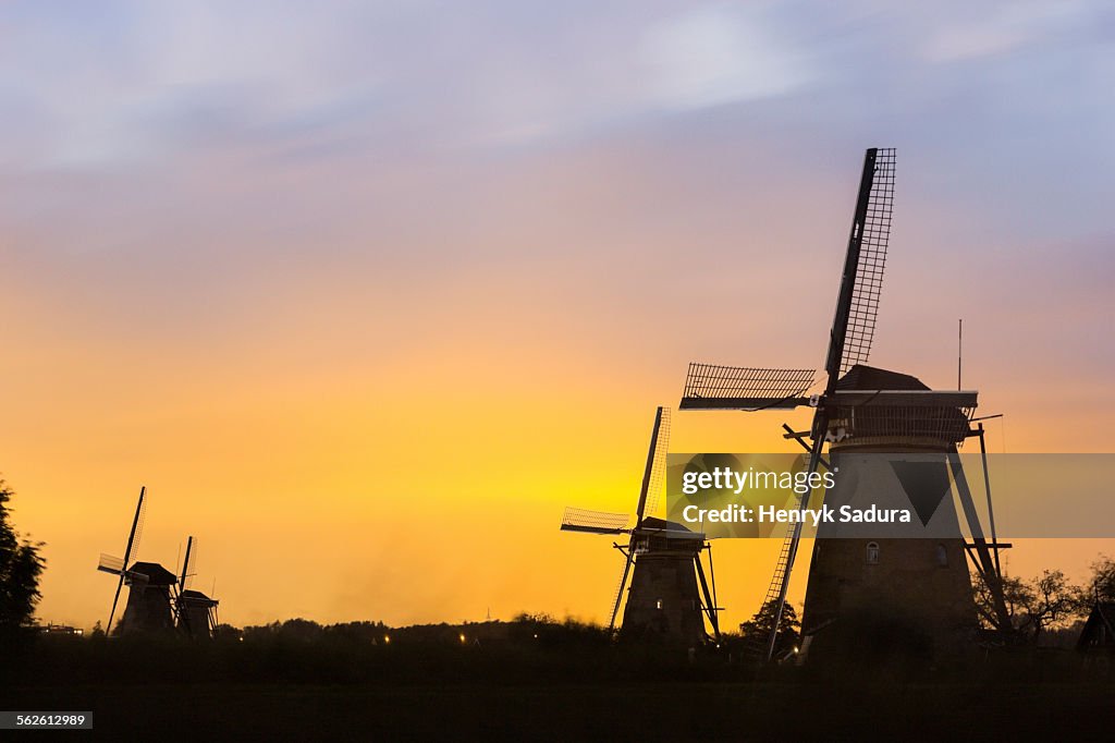 Netherlands, South Holland, Kinderdijk, Winmills silhouetted against sunset sky