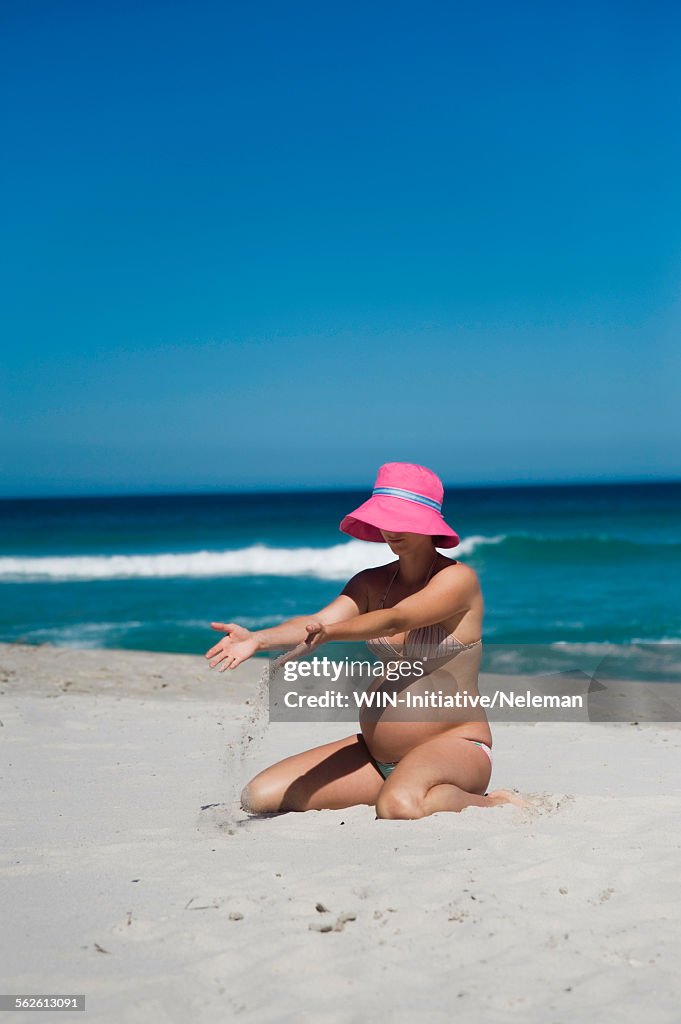 Pregnant woman kneeling on the beach, Cape Town, South Africa