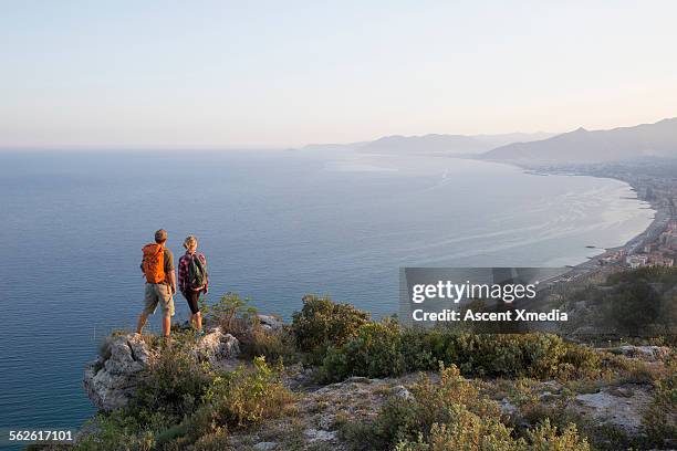 young hiking couple pause to look across sea, town - liguria imagens e fotografias de stock