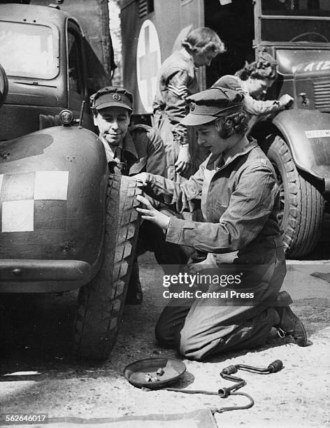 Princess Elizabeth changing the tire of a vehicle as she trains at as ATS Officer during World War Two, at the ATS training centre in England, April...