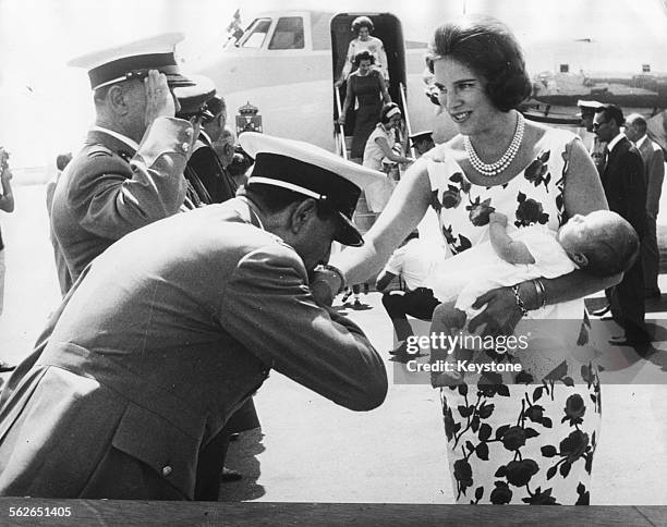 Queen Anne Marie of Greece holding her baby daughter, Crown Princess Alexia, as her hand is kissed by a member of the plane crew as they arrive in...