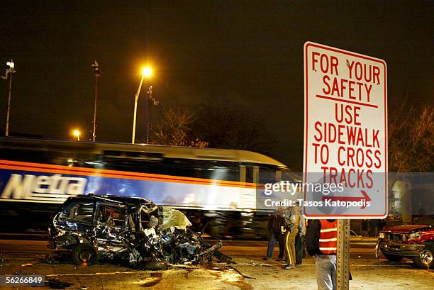 As another Metra train passes, workers stand amidst stand amidst the wreckage after a Metra train crashed into about five vehicles, which hit another...