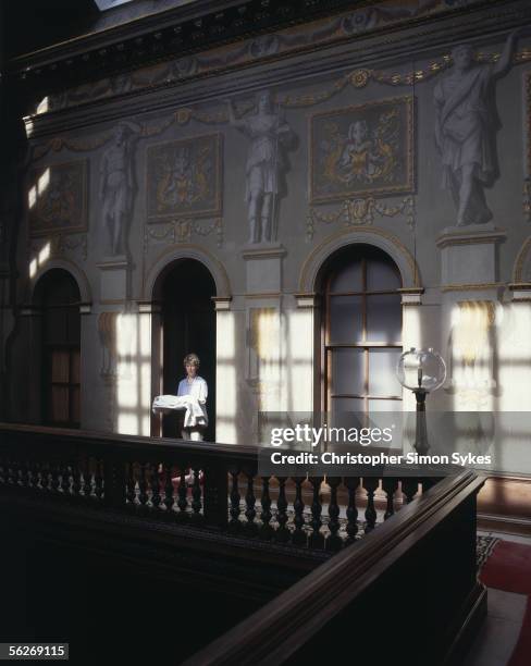 The housekeeper of Houghton Hall, Norfolk, 1990s. Roman figures adorn the wall behind her.