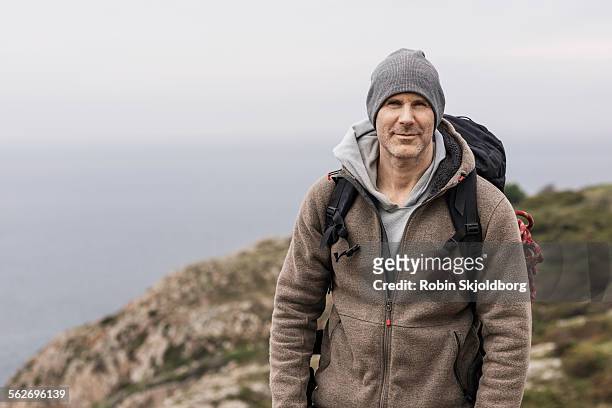 portrait of man with hat and rucksack - landskap stockfoto's en -beelden