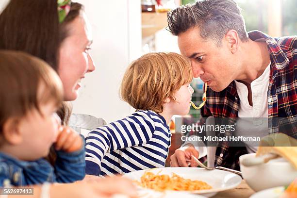 father and son eating same peice of pasta - family eating stock pictures, royalty-free photos & images