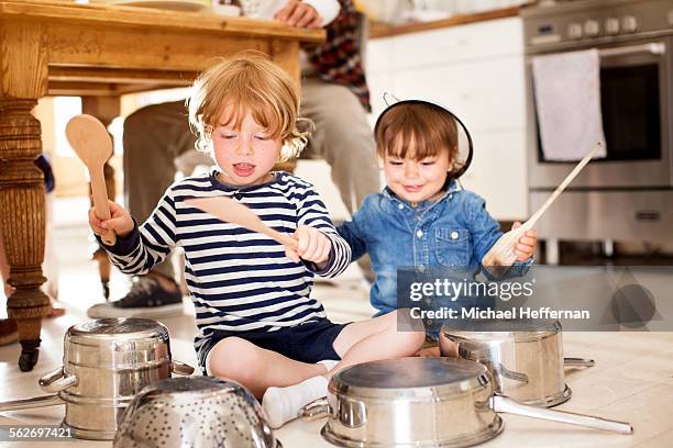 two boys playing on floor with pots and pans - drum percussion instrument stock-fotos und bilder