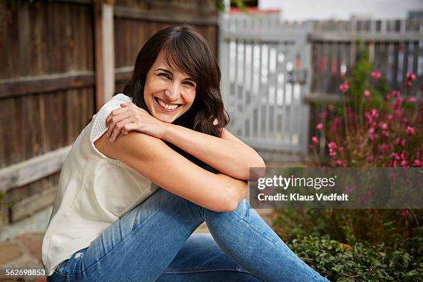 portrait of beautiful woman smiling to camera - hugging knees - fotografias e filmes do acervo