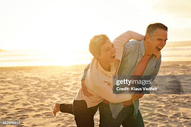 mature couple laughing & hugging on beach - couple short hair stock-fotos und bilder