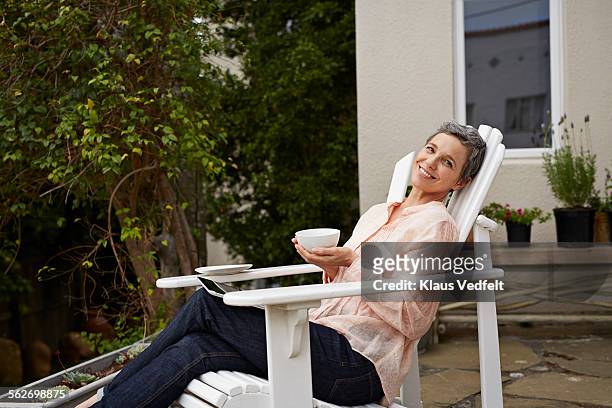 mature woman relaxing with tea and digital tablet - té terraza fotografías e imágenes de stock