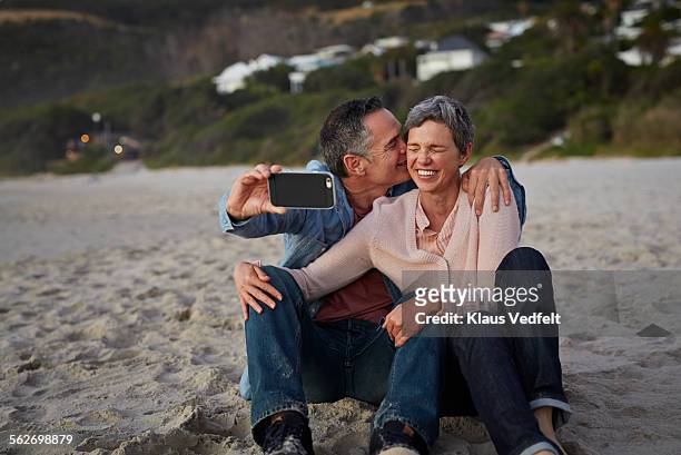 mature man kissing girlfriend while making selfie - 50 59 years stock pictures, royalty-free photos & images