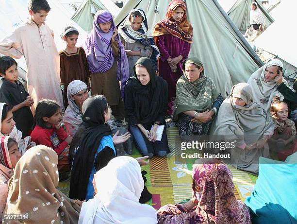 In this handout photo from United Nations Humanitarian Commitee of Refugees, Goodwill Ambassador Angelina Jolie talks with women who survived the...
