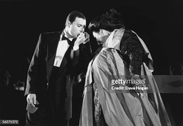 Singer Freddie Mercury kisses opera singer Montserrat Caballe on the hand as they perform 'Barcelona' at a music festival in the city to celebrate...