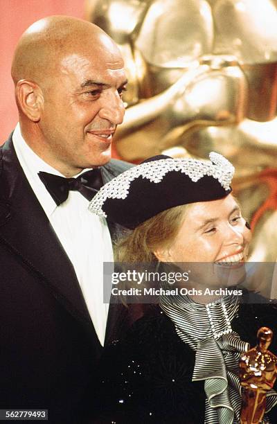 Actor Telly Savalas poses backstage with Ulla-Britt Soderlund winner of "Best Costume Design" award during the 48th Academy Awards at Dorothy...