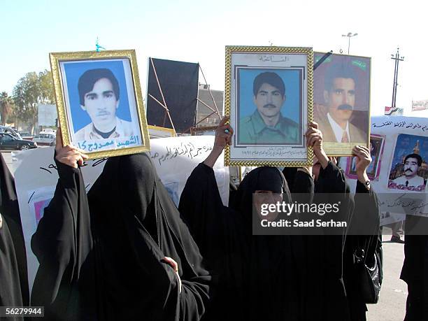 Iraqis carriy pictures of their relatives executed after the 1991 Shiite uprising as she takes part in a protest demanding the execution of Iraq's...