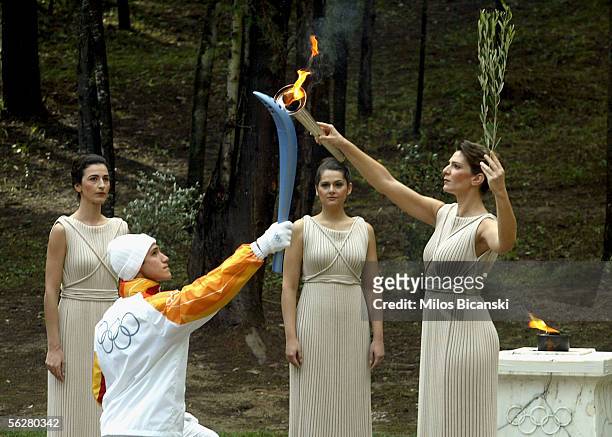 Greek athlete Costas Fillipidis, the first torchbearer, recives the flame from actress Theodora Siarkou who plays the role of high priestess during...
