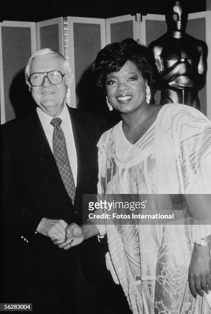 American film director Robert Wise shakes hands with American television personality, actress, and producer Oprah Winfrey backstage at the Academy...
