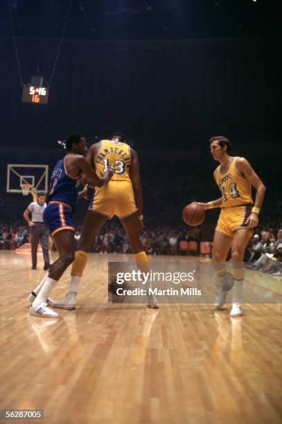 Jerry West of the Los Angeles Lakers moves the ball behind a screen set by teammate Wilt Chamberlain against the New York Knicks during a 1971 NBA...