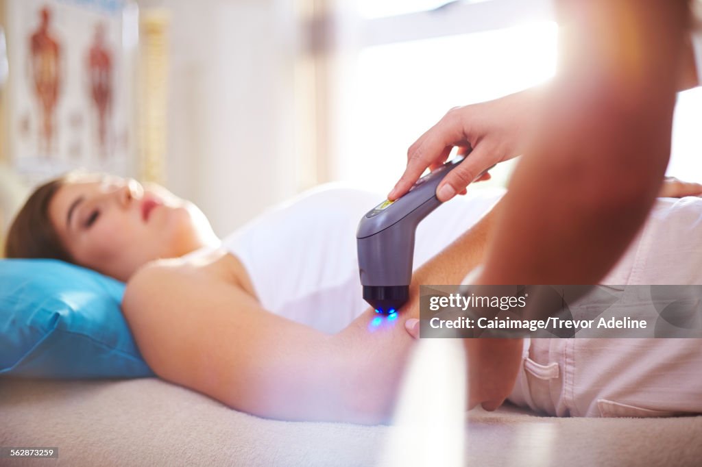 Physical therapist using ultrasound probe on womans arm
