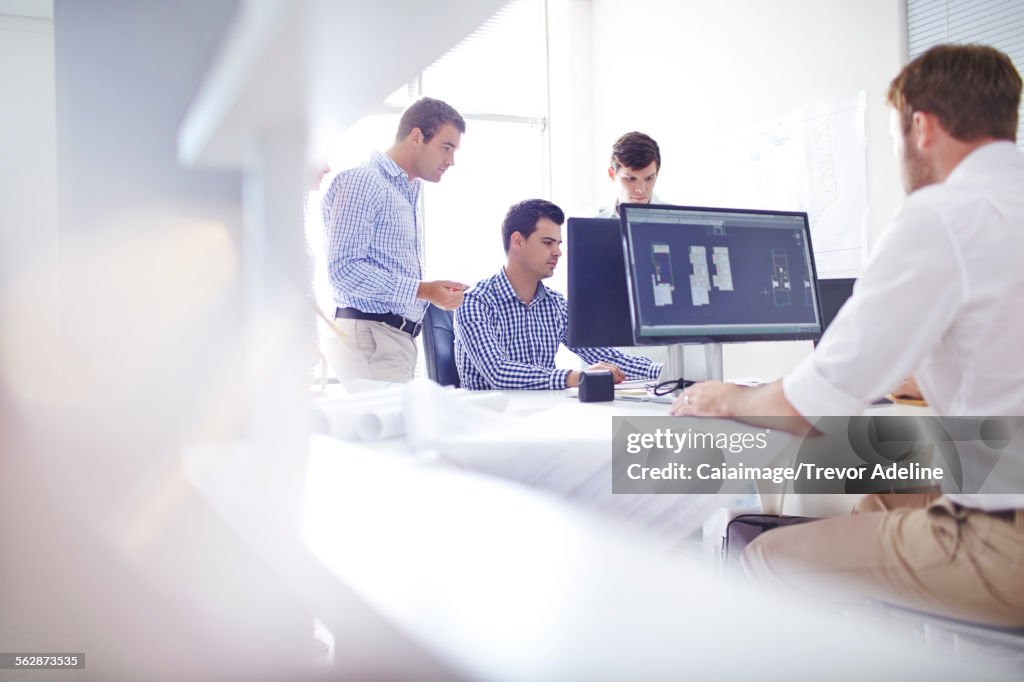 Architects drafting blueprints at computers in office