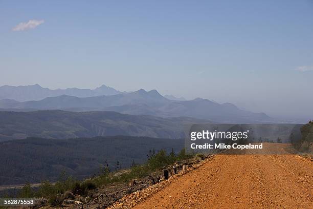 the gravel road between avontuur and plettenberg bay winds down the prince alfreds pass and through the blue haze of the outeniqua mountains, western cape, south africa. - avontuur foto e immagini stock