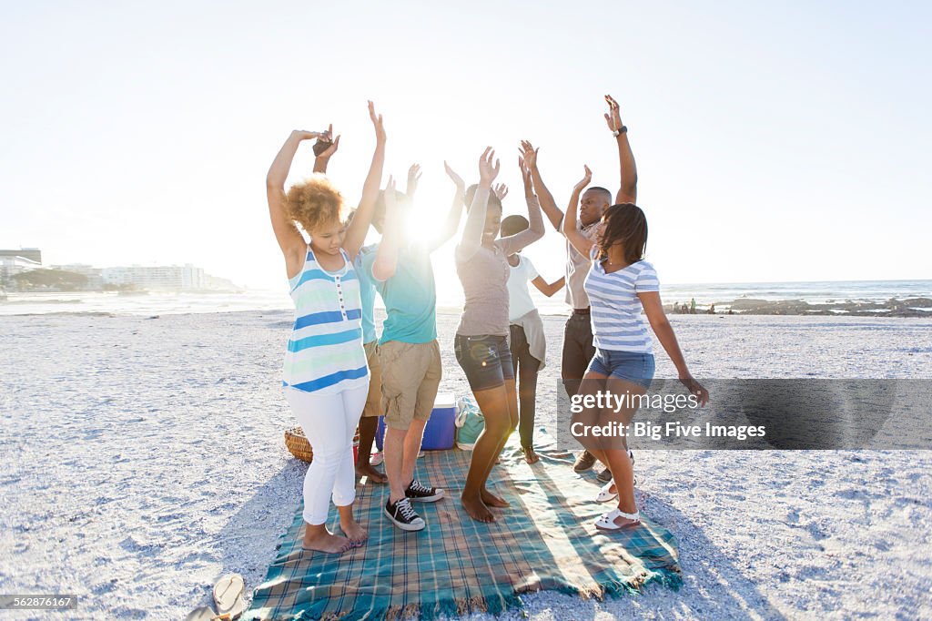 Group of teens having fun dancing on the beach after a picnic, Cape Town, Western Cape, South Africa.