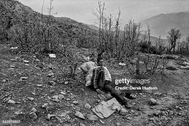 Young man resting from carrying his entire possessions on his back as he descends a mountain path towards the refugee camp at Isikveren. The Iraqi...