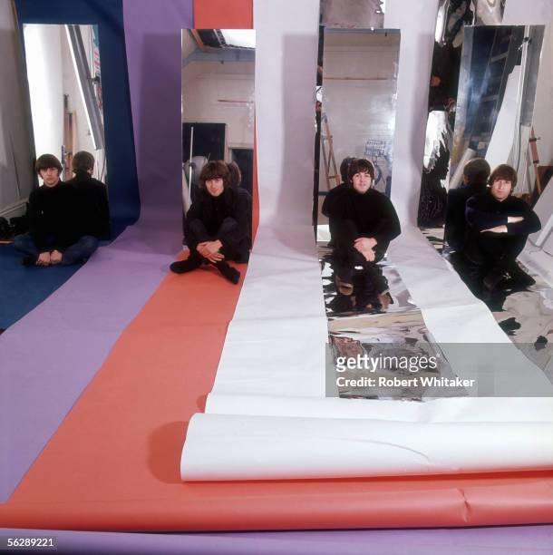 The Beatles sitting on rolls of coloured paper in a photographic studio, 1966.